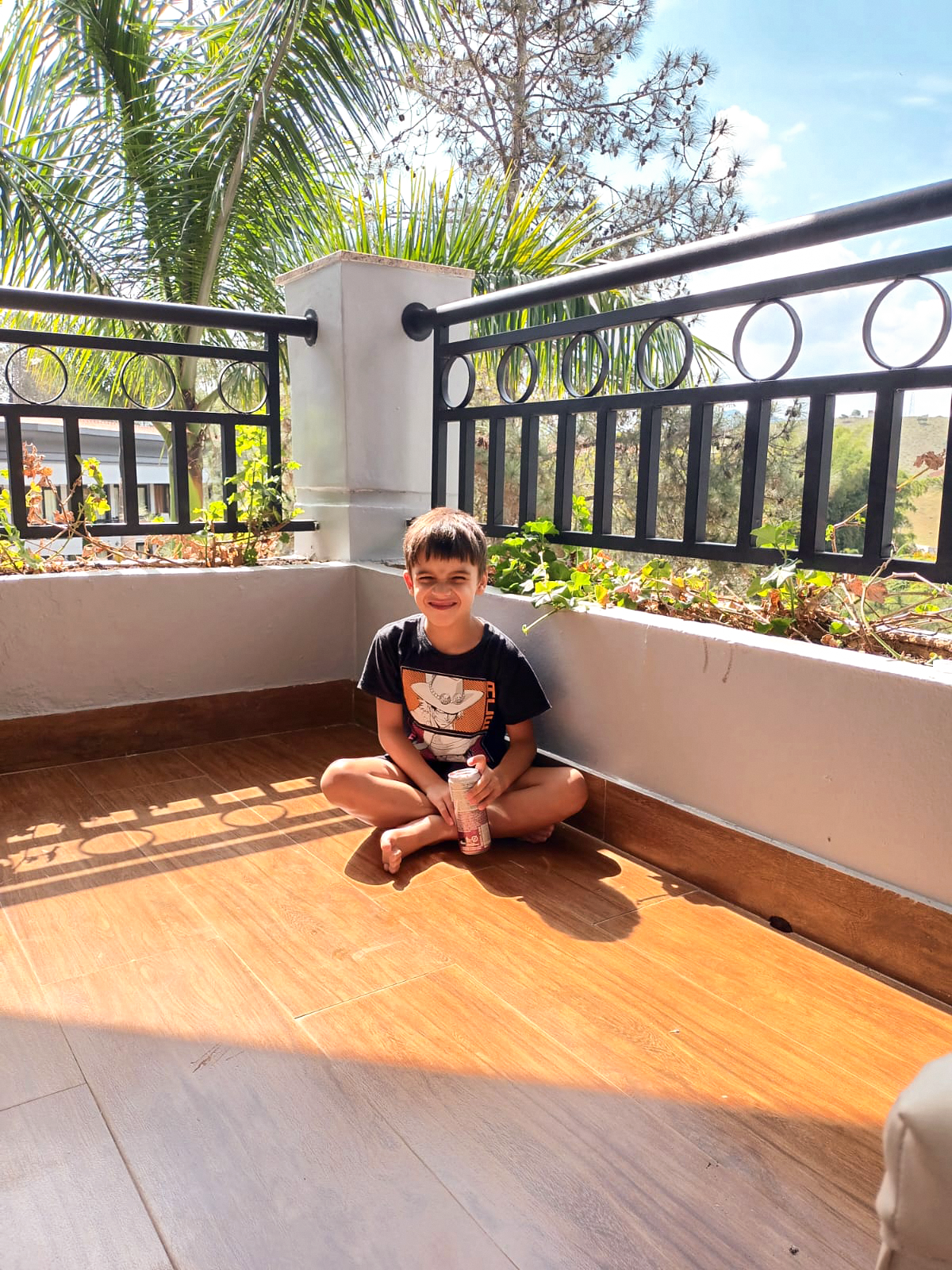 thales sentado ao canto de uma varanda com a luz solar refletindo em seu rosto
